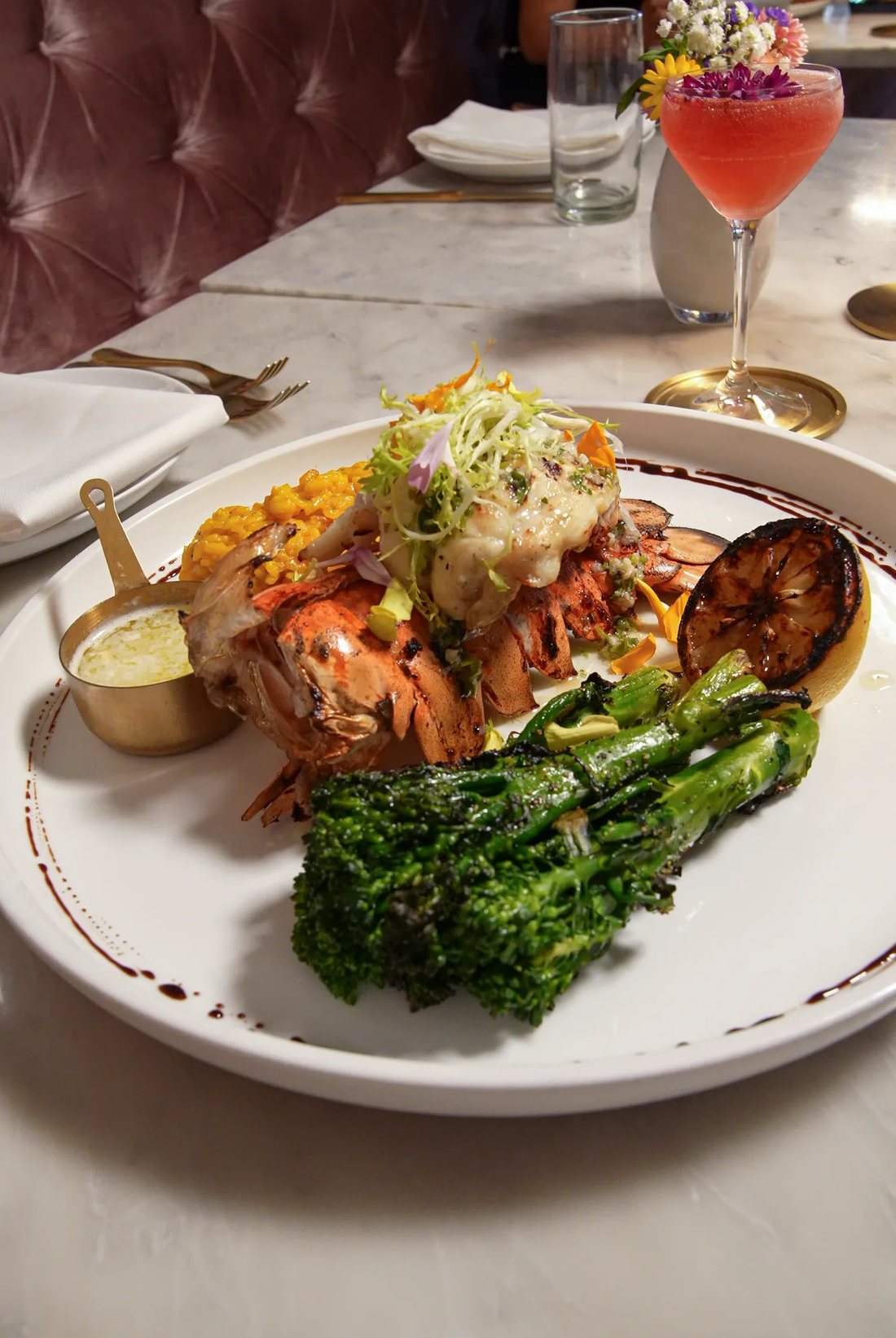 Jumbo lobster tail with broccolini on a marble table at Flowers Saratoga